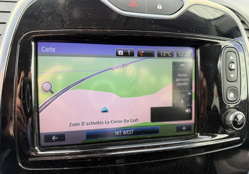 Écran tactile GPS du tableau de bord noir brillant d'un Renault Captur blanc, affichant une carte de navigation.