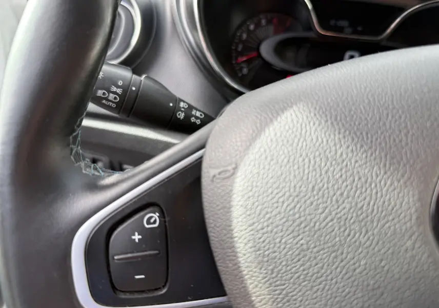 Gros plan sur le volant noir du Renault Captur 2017 avec commandes intégrées et tableau de bord en arrière-plan flou.