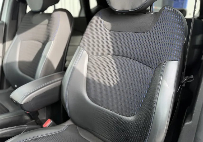 Gros plan sur les sièges avant en tissu et cuir noir avec surpiqûres bleues du Renault Captur blanc 2017.
