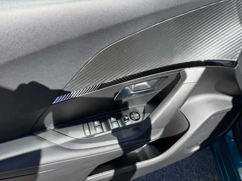 Détail de la porte côté gauche du Peugeot 2008 2025 Bleu Obsession avec commandes de vitres et insert décoratif noir brillant.