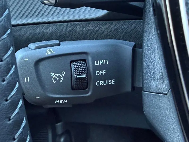 Gros plan sur la commande de régulateur de vitesse du Peugeot 2008 1.2 Hybrid 145ch Allure en intérieur noir.