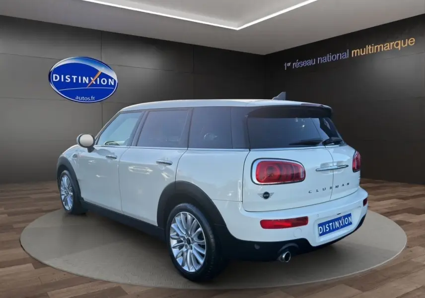Vue 3/4 arrière droite d'une MINI Clubman blanche avec toit noir, feux arrière caractéristiques et jantes alliage.