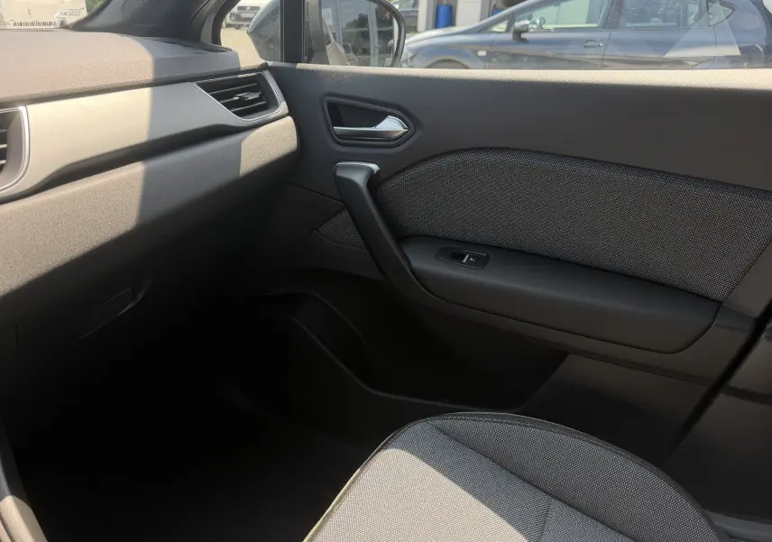Vue intérieure côté passager du Renault Captur 2026, montrant la porte et le siège en tissu gris.
