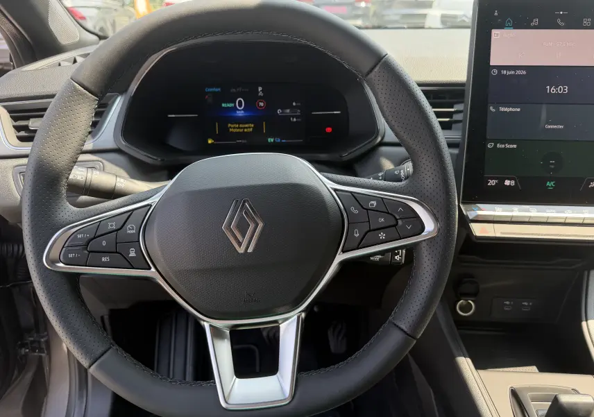 Vue intérieure centrée sur le volant noir perforé du Renault Captur 2026 avec tableau de bord numérique et écran tactile.