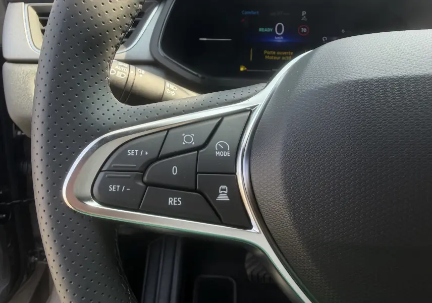 Gros plan sur les commandes gauche du volant textile perforé du Renault Captur 1.8 E-Tech hybride 2026.