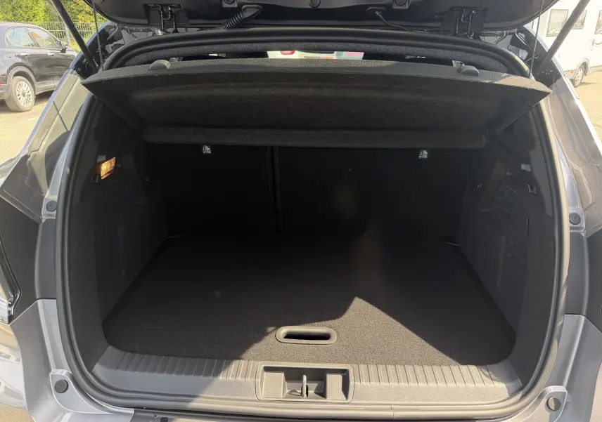 Coffre ouvert vu de l'arrière du Renault Captur gris Cassiopée bi-ton, montrant l'espace de rangement vide et la tablette cache-bagages.