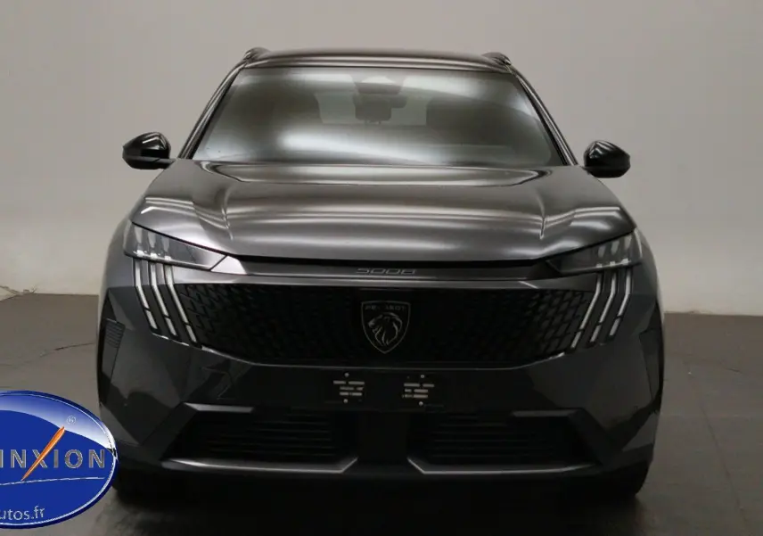 Vue frontale du Peugeot 5008 III Hybrid 145 gris titane avec calandre noire et signature lumineuse verticale LED.
