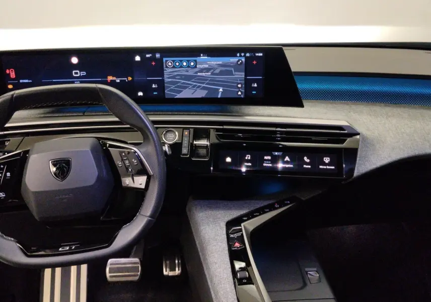 Vue intérieure du tableau de bord du Peugeot 5008 III Hybrid 145 GT avec volant multifonction et écrans numériques.