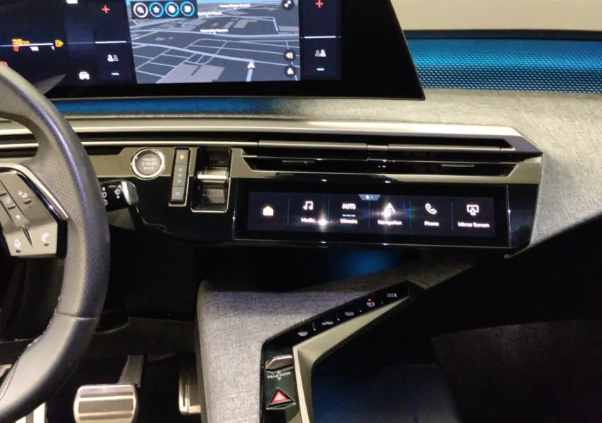 Vue intérieure du tableau de bord du Peugeot 5008 III Hybrid gris titane, avec écran tactile central et volant partiel visible.