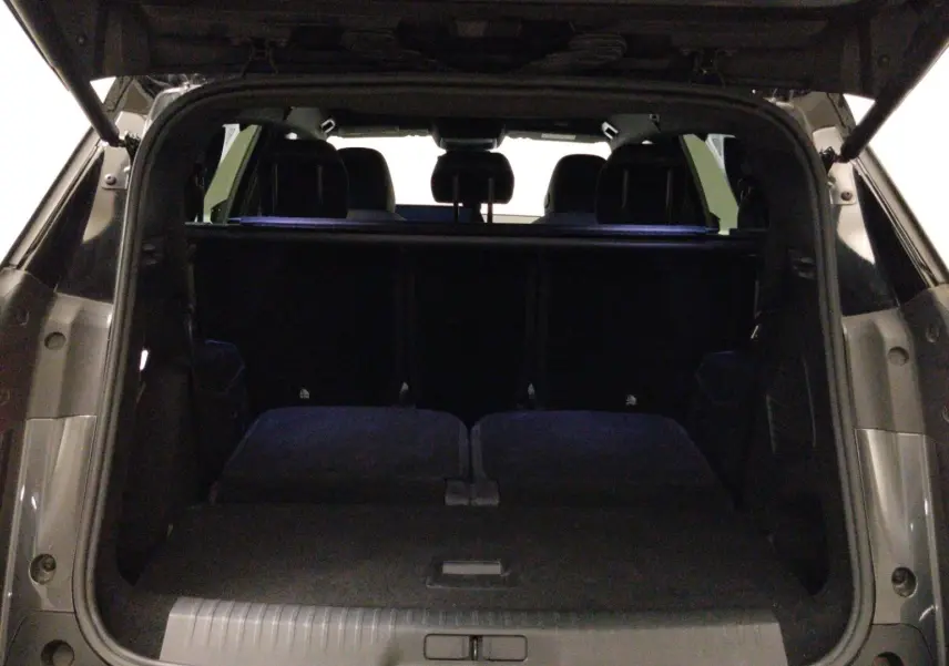 Coffre ouvert vu de l'arrière du Peugeot 5008 gris titane, montrant l'espace de chargement et les sièges arrière rabattus.