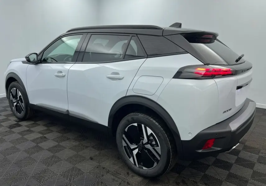 Vue 3/4 arrière droite du Peugeot 2008 Hybrid 145 GT blanc avec toit noir et feux arrière allumés.