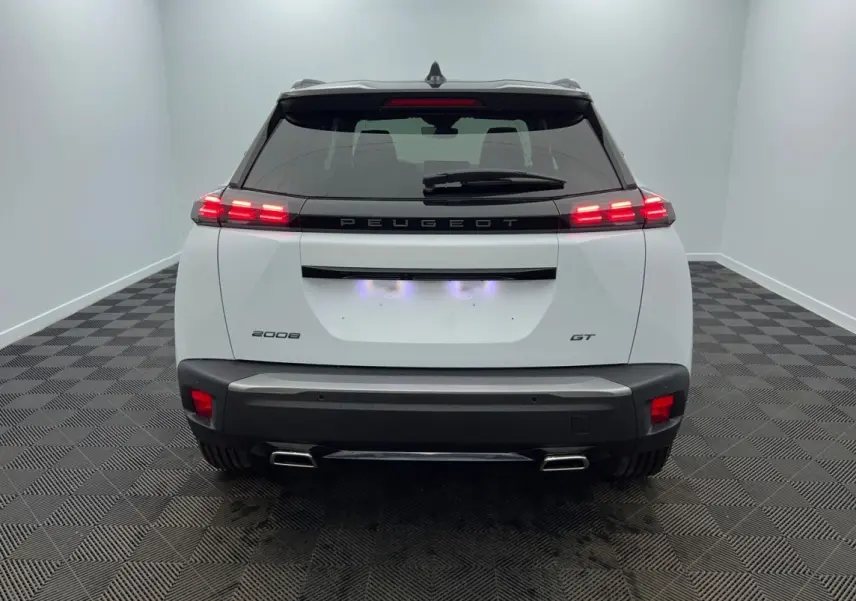 Vue arrière d'un Peugeot 2008 blanc avec feux LED allumés et double sortie d'échappement chromée.