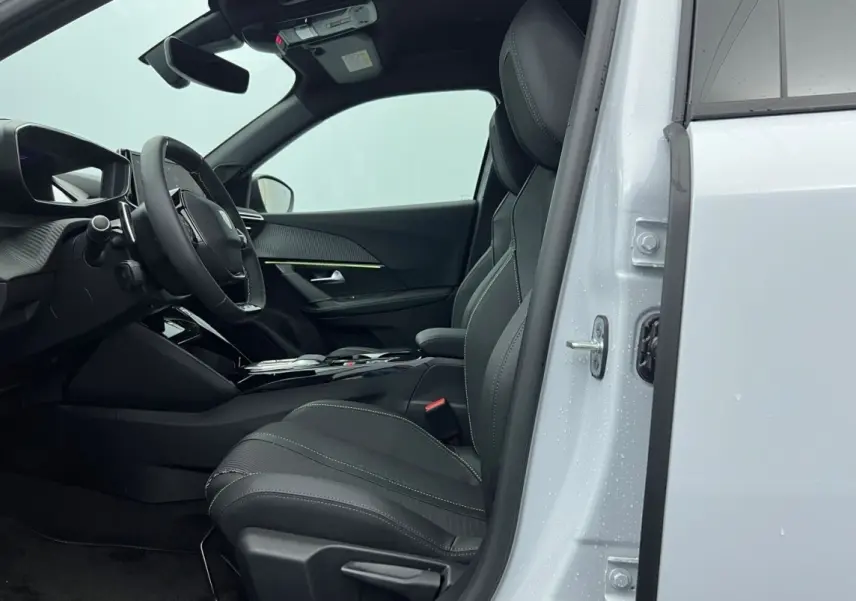 Vue intérieure côté conducteur du Peugeot 2008 Hybrid blanc, mettant en valeur le siège et le volant cuir multifonctions.