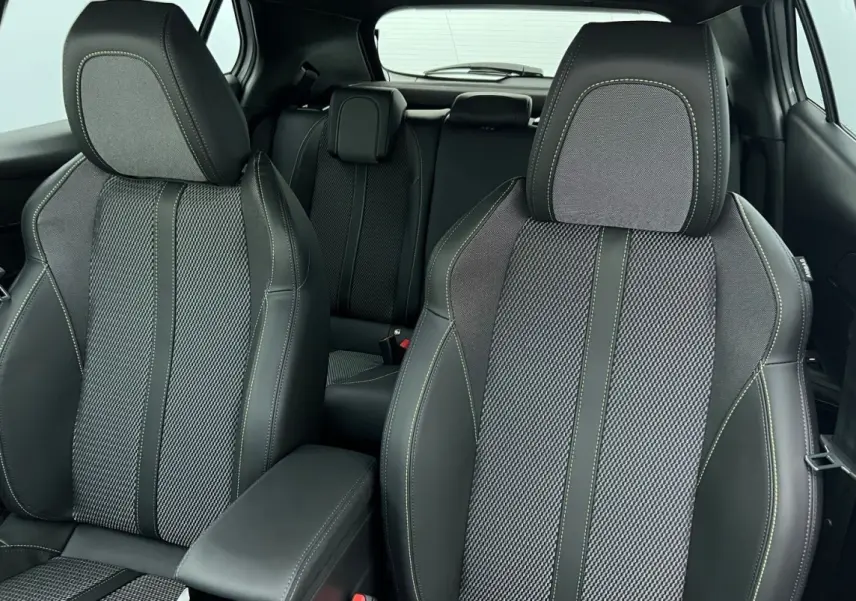 Vue intérieure des sièges avant et arrière en tissu noir et gris du Peugeot 2008 Hybrid 145 e-DCS6 GT.