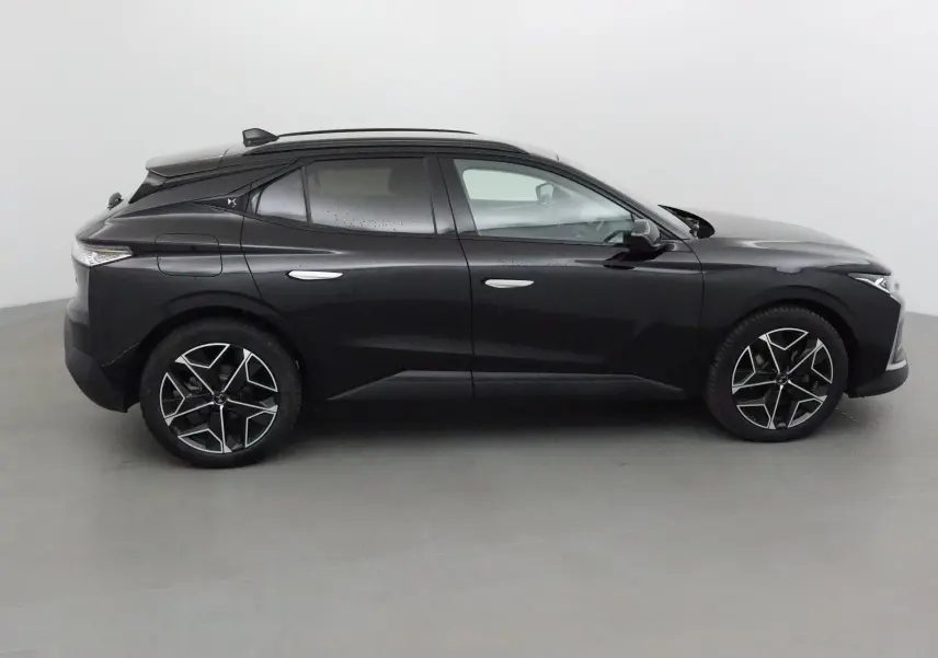 Profil côté gauche d'une DS4 noire 2022 avec jantes alliage noires et toit panoramique, dans un studio lumineux.
