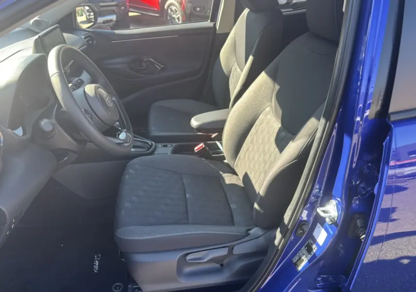 Vue intérieure côté conducteur de la Toyota Yaris 1.5 Hybrid 116 BVA Design 2025 en bleu genievre, sièges tissu gris.