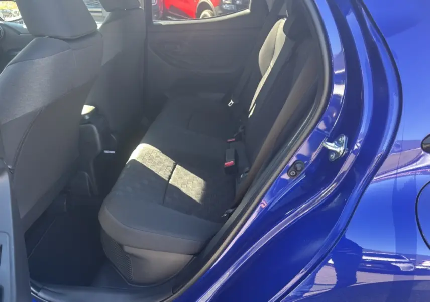 Vue intérieure sur la banquette arrière côté gauche d'une Toyota Yaris 1.5 Hybrid 2025 bleu genievre avec sièges tissu noir.