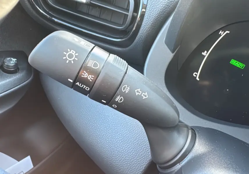 Gros plan sur la commande des feux et clignotants à gauche du volant d'une Toyota Yaris 1.5 Hybrid 2025.