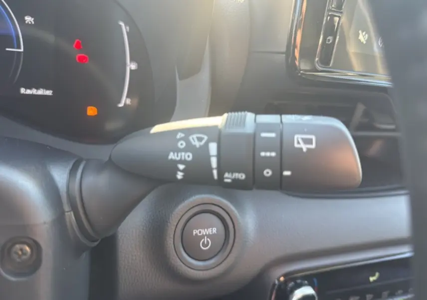 Détail intérieur du Toyota Yaris 2025 montrant la commande d'essuie-glace et le bouton Power sur tableau de bord noir.