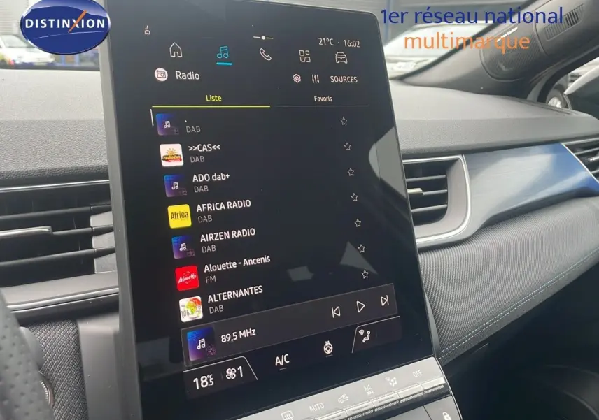 Écran tactile central du Renault Captur E-Tech blanc nacré, affichant les options radio et climatisation dans l'habitacle.