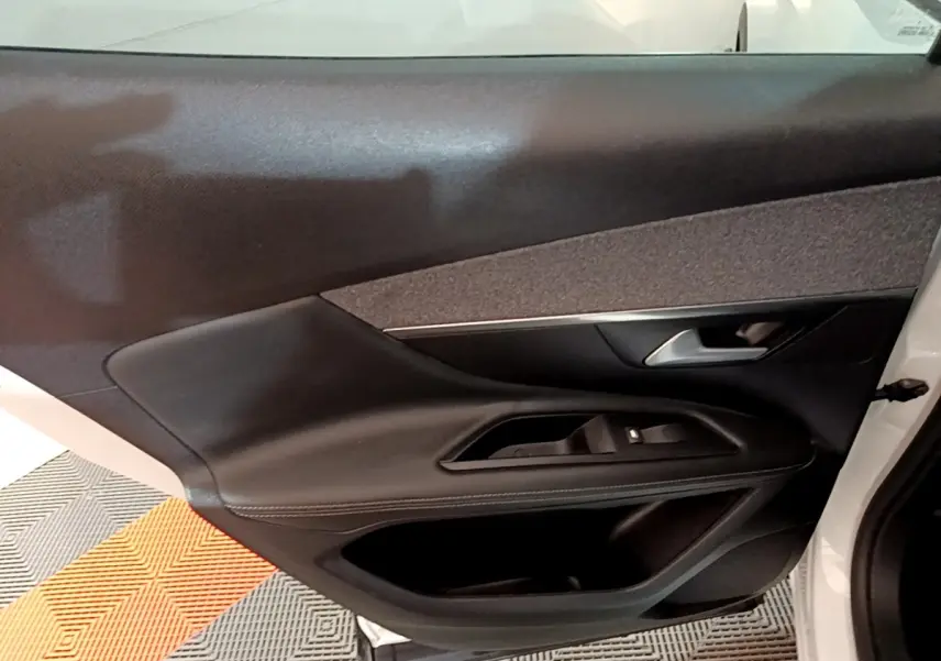 Gros plan sur la porte avant droite noire du Peugeot 3008 blanc, mettant en valeur les commandes de vitre et la poignée.