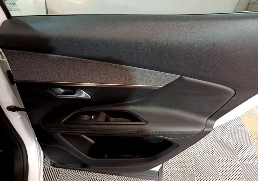 Vue intérieure de la porte côté gauche du Peugeot 3008 blanc, avec garniture noire et commandes électriques.