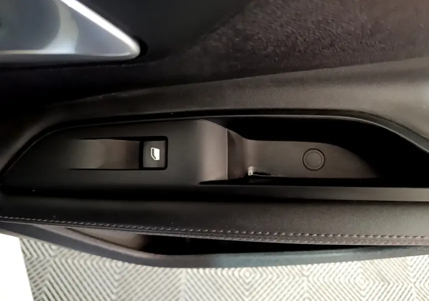 Gros plan sur la commande de lève-vitre côté gauche intérieur d’un Peugeot 3008 blanc hybride rechargeable.
