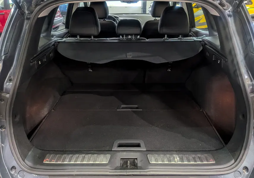 Vue depuis le coffre ouvert d’un Renault Kadjar gris titanium, montrant le grand espace de chargement et la banquette arrière.