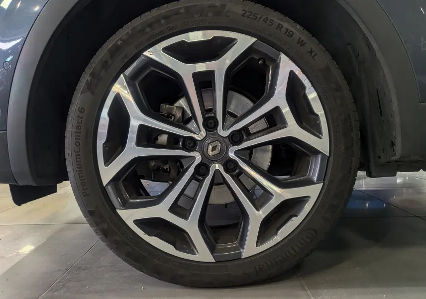 Gros plan sur la roue avant droite du Renault Kadjar gris titanium, mettant en valeur la jante alliage bicolore au design moderne.