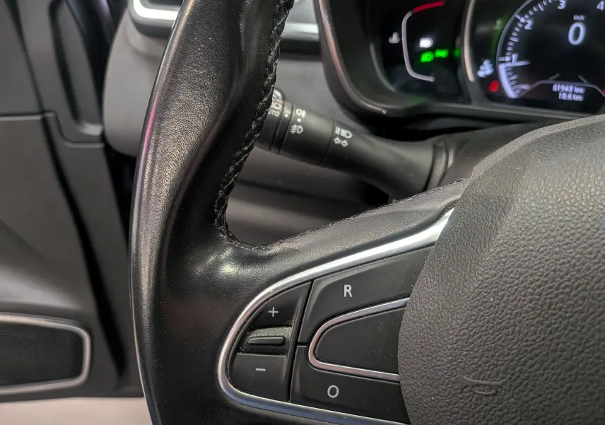 Gros plan sur le volant en cuir noir du Renault Kadjar TCe 140 CH Intens, avec commandes intégrées et tableau de bord partiellement visible.