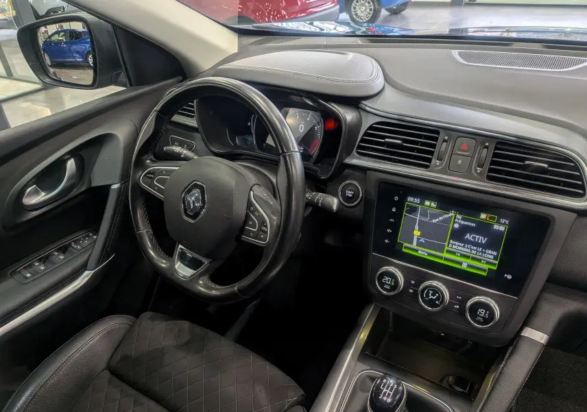 Vue intérieure côté conducteur du Renault Kadjar TCe 140 Intens 2019, volant cuir noir et écran tactile central allumé.