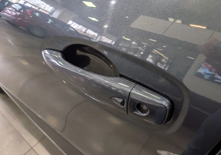 Poignée de porte côté gauche gris titanium du Renault Kadjar TCe 140 CH INTENS 2019 avec serrure visible en gros plan.