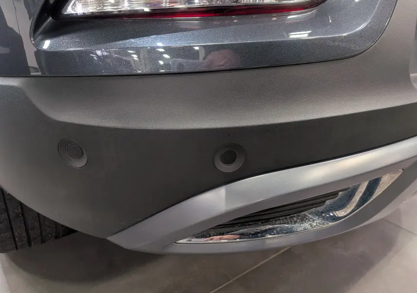 Gros plan sur le pare-chocs arrière gris titanium du Renault Kadjar TCe 140 CH INTENS avec capteurs de recul visibles.