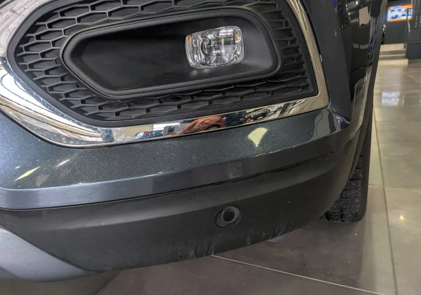 Gros plan sur le pare-chocs avant droit gris titanium du Renault Kadjar TCe 140 CH Intens avec antibrouillard et radar de recul.