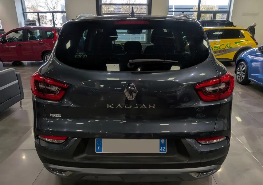 Vue arrière d'un Renault Kadjar gris titanium 2019 dans un showroom, avec feux arrière LED et logo central visible.