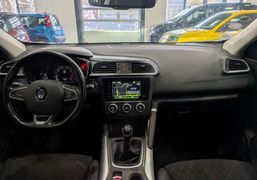 Vue intérieure avant du Renault Kadjar TCe 140 Intens 2019, tableau de bord noir avec écran tactile et levier de vitesses manuel.