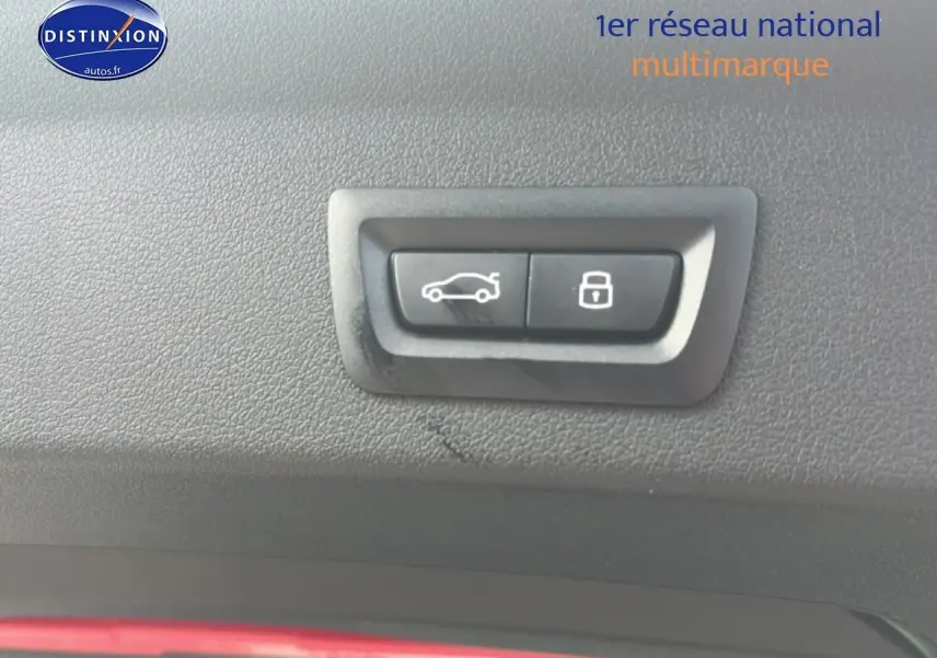 Boutons d'ouverture de coffre et de verrouillage intégrés dans le panneau intérieur noir d'une BMW Série 1 blanche.