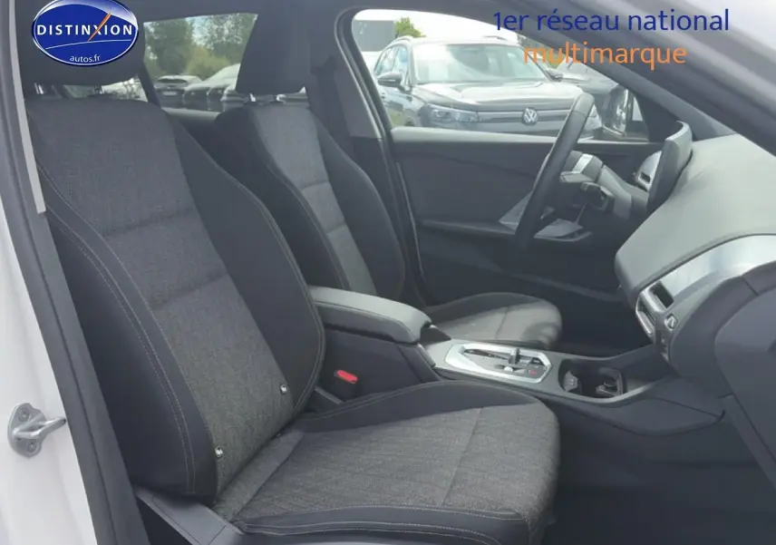 Vue intérieure côté conducteur de la BMW Série 1 blanche, montrant sièges sport et console centrale avec boîte auto.