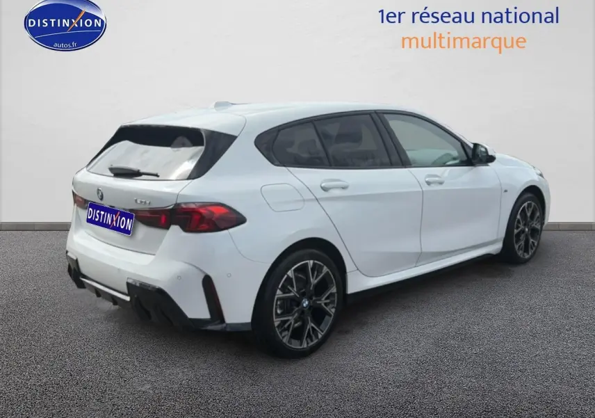 BMW Série 1 blanche vue 3/4 arrière droit, avec jantes alliage noires et feux arrière LED distinctifs.