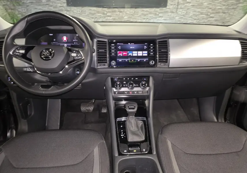 Vue intérieure avant du Skoda Kodiaq noir 2023, tableau de bord moderne avec écran tactile et levier de vitesses automatique.