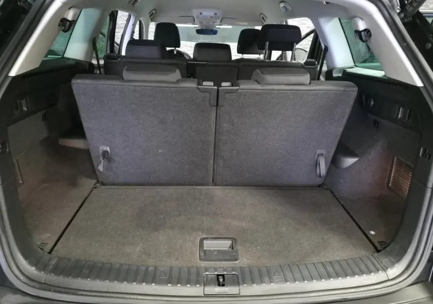 Coffre ouvert vu de l'arrière d'un Skoda Kodiaq noir 7 places avec banquette arrière relevée et intérieur tissu gris.