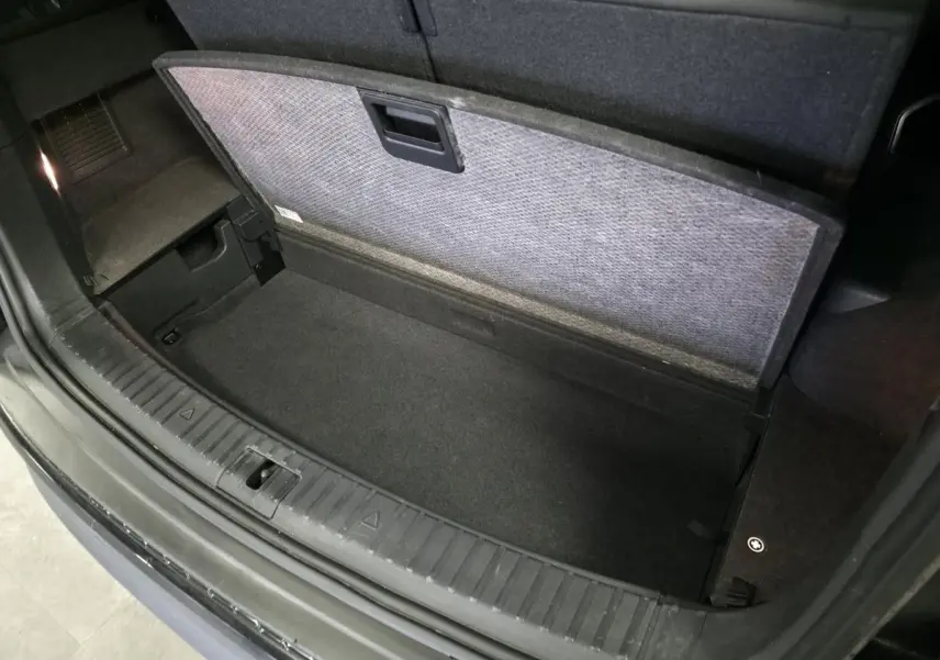 Coffre ouvert vu de dessus d’un Skoda Kodiaq noir 2023 avec compartiment de rangement sous plancher.