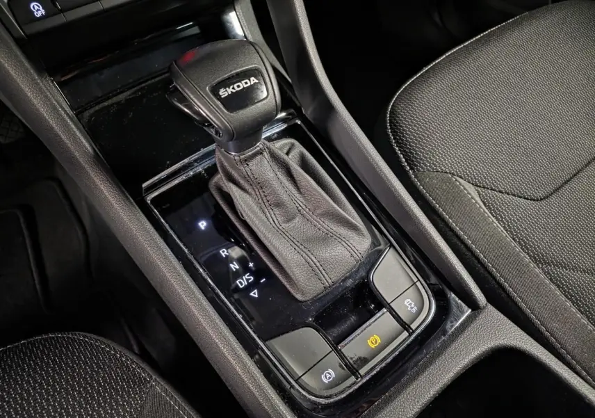 Gros plan sur la console centrale noire du Skoda Kodiaq 2023, avec levier de vitesses automatique et sellerie tissu noire.