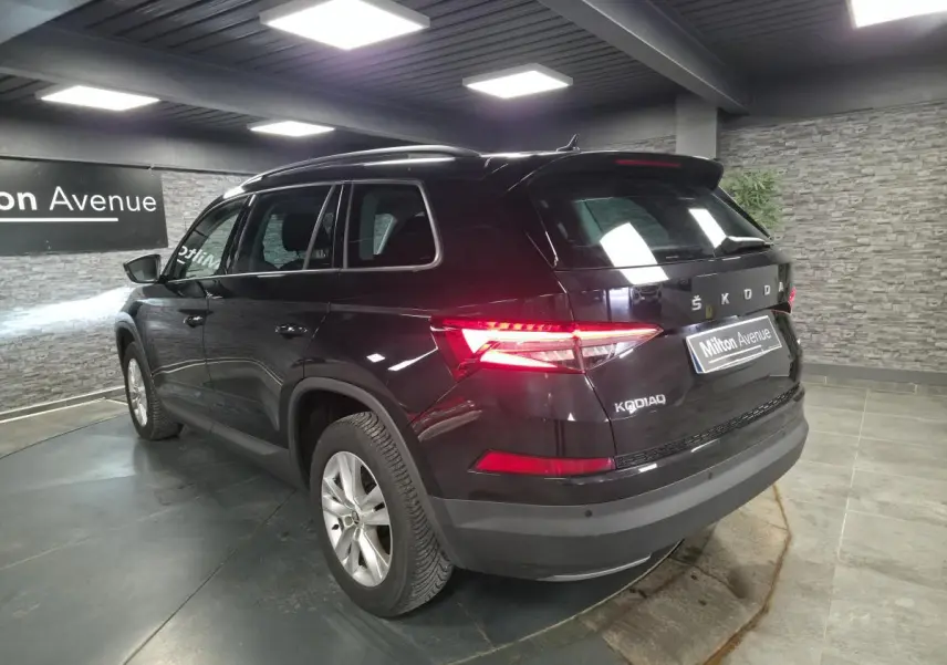 Vue 3/4 arrière droite d'un Skoda Kodiaq noir avec feux arrière allumés dans un showroom.