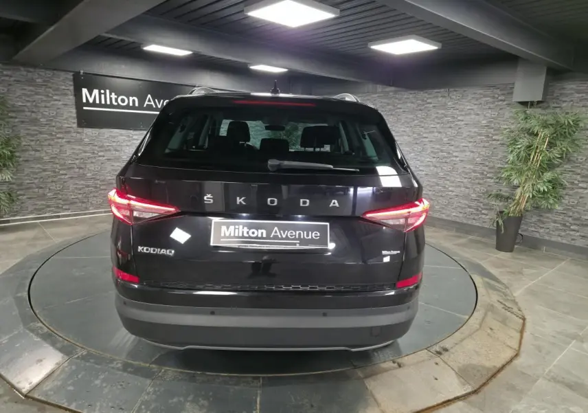 Vue arrière d'un Skoda Kodiaq noir 2023 avec feux arrière LED allumés dans un showroom intérieur.
