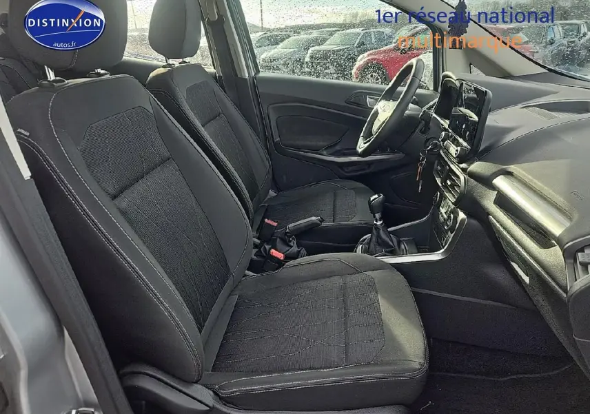 Vue intérieure côté conducteur du Ford EcoSport gris 2019, montrant les sièges en tissu noir et la console centrale avec boîte manuelle.