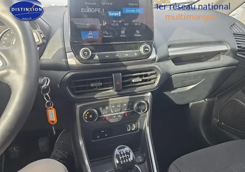 Vue intérieure avant du Ford EcoSport gris 2019, mettant en valeur la console centrale avec écran tactile et levier de vitesse manuel.