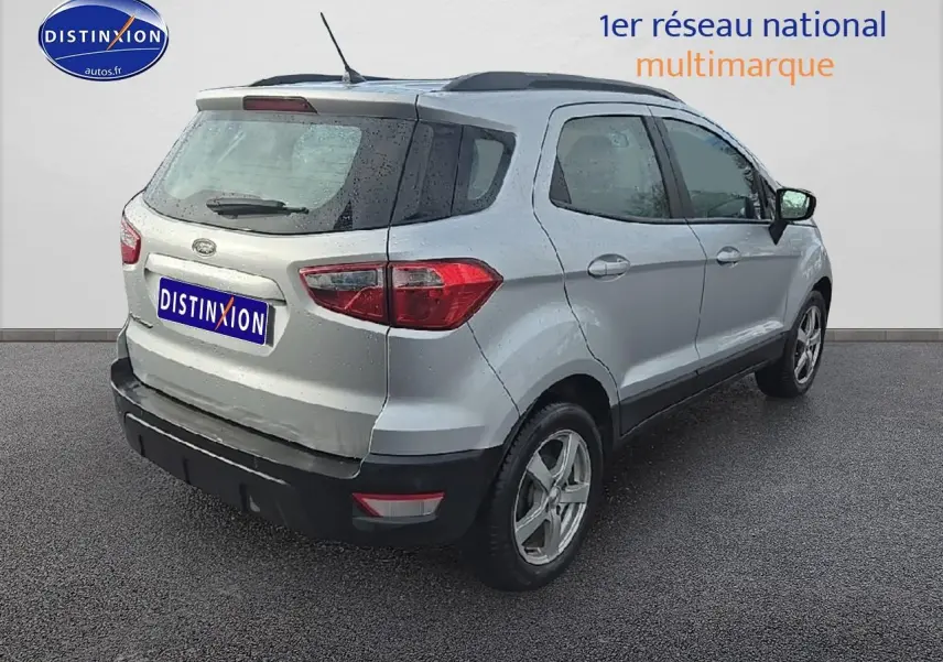 Vue 3/4 arrière droite d'un Ford EcoSport gris 2019 avec jantes alu et barres de toit noires.