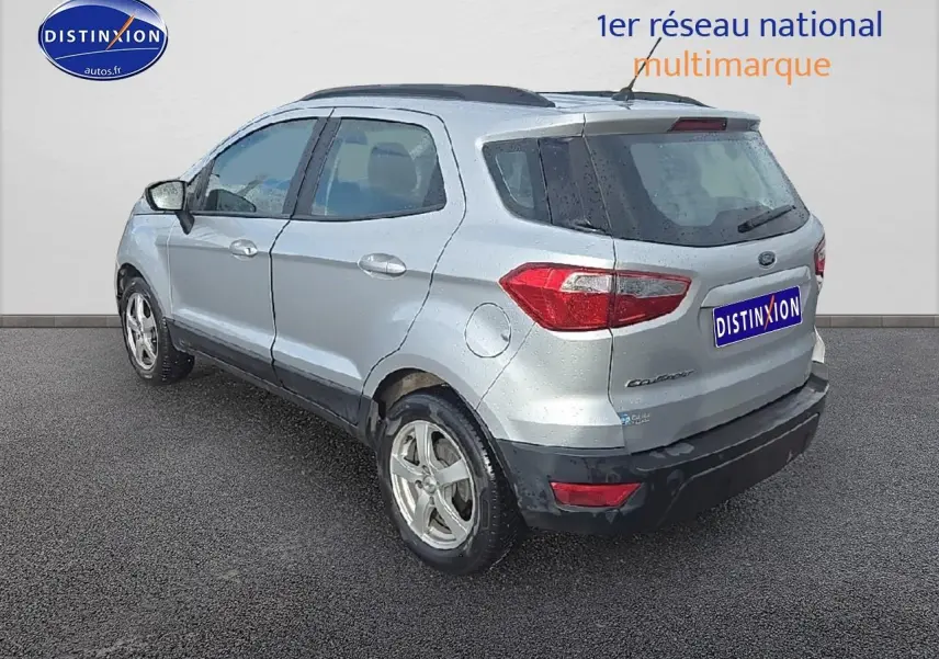 Vue 3/4 arrière droite d'un Ford EcoSport gris 2019 avec jantes alu et barres de toit noires.