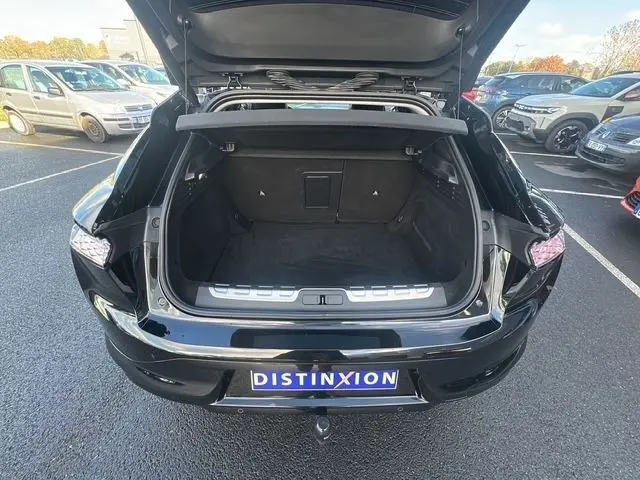 Vue arrière ouverte du coffre d'une DS4 noire 2022, soulignant l'espace de chargement et le spoiler de coffre.